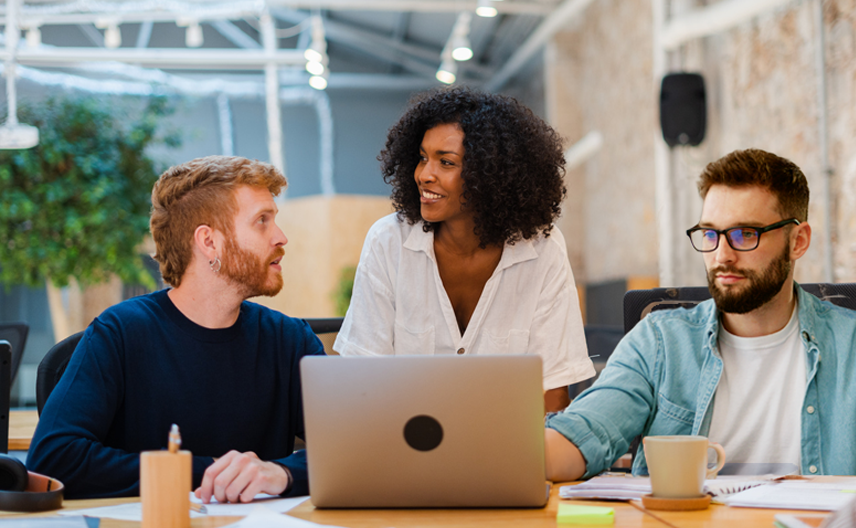 3 Personen besprechen einen Entwurf auf einem Laptop