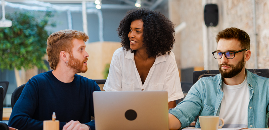 3 Personen besprechen einen Entwurf auf einem Laptop