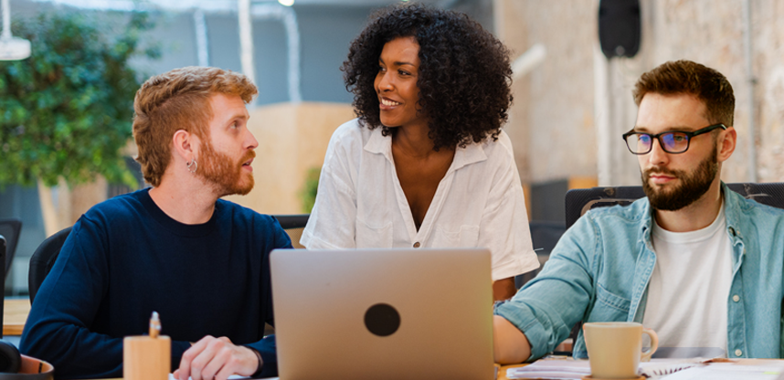 3 Personen besprechen einen Entwurf auf einem Laptop