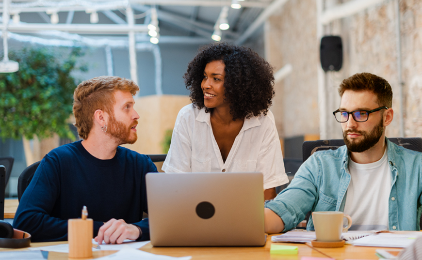 3 Personen besprechen einen Entwurf auf einem Laptop
