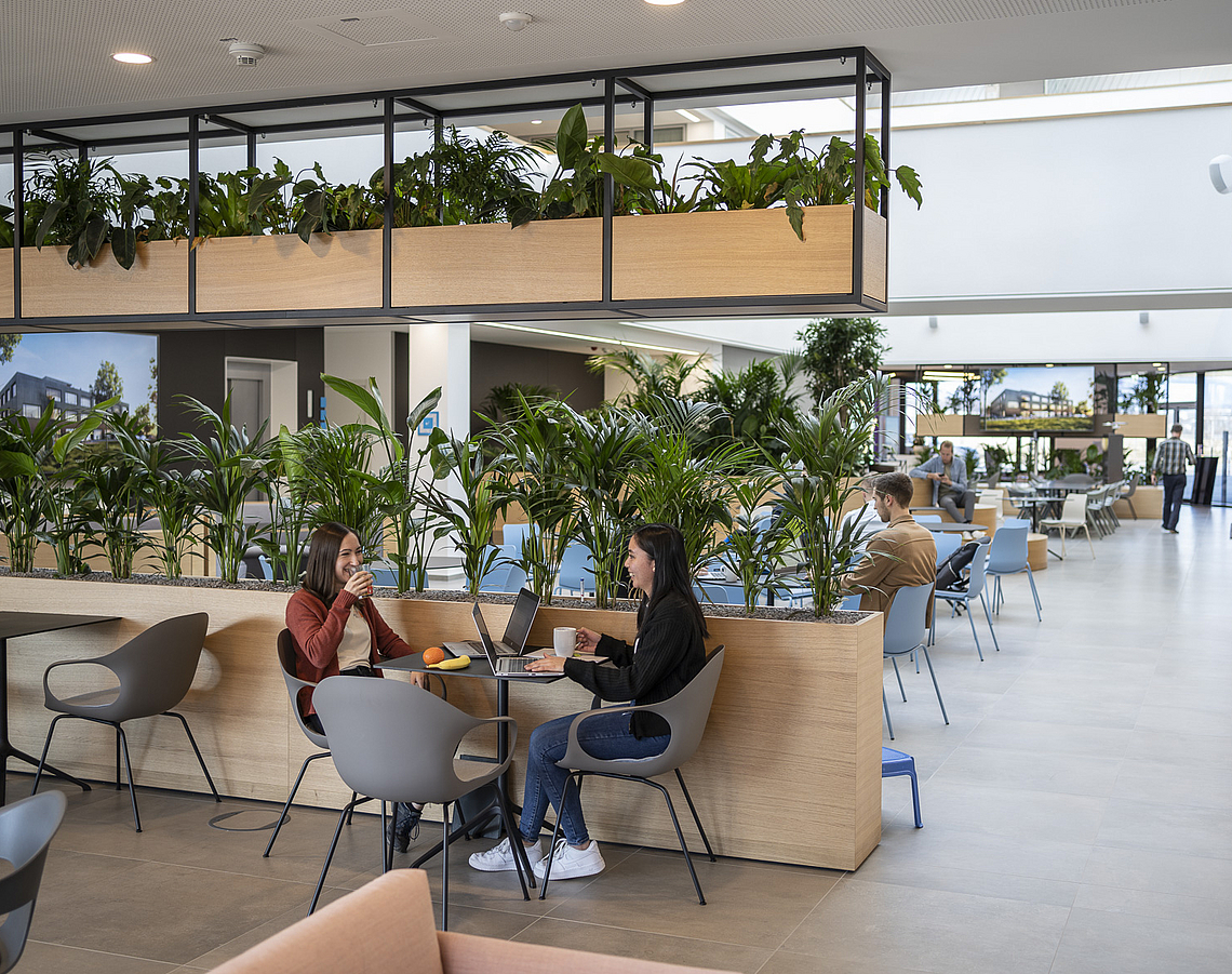 Zwei Frauen sitzen im Atrium des Software Innovationszentrums und trinken Kaffee