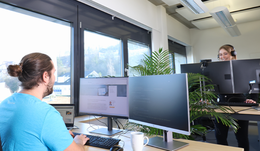 Mann sitzt am Schreibtisch und programmiert Mann sitzt am Schreibtisch und programmiert