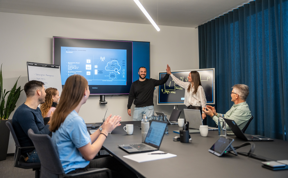 Two employees give each other a high five in a meeting room