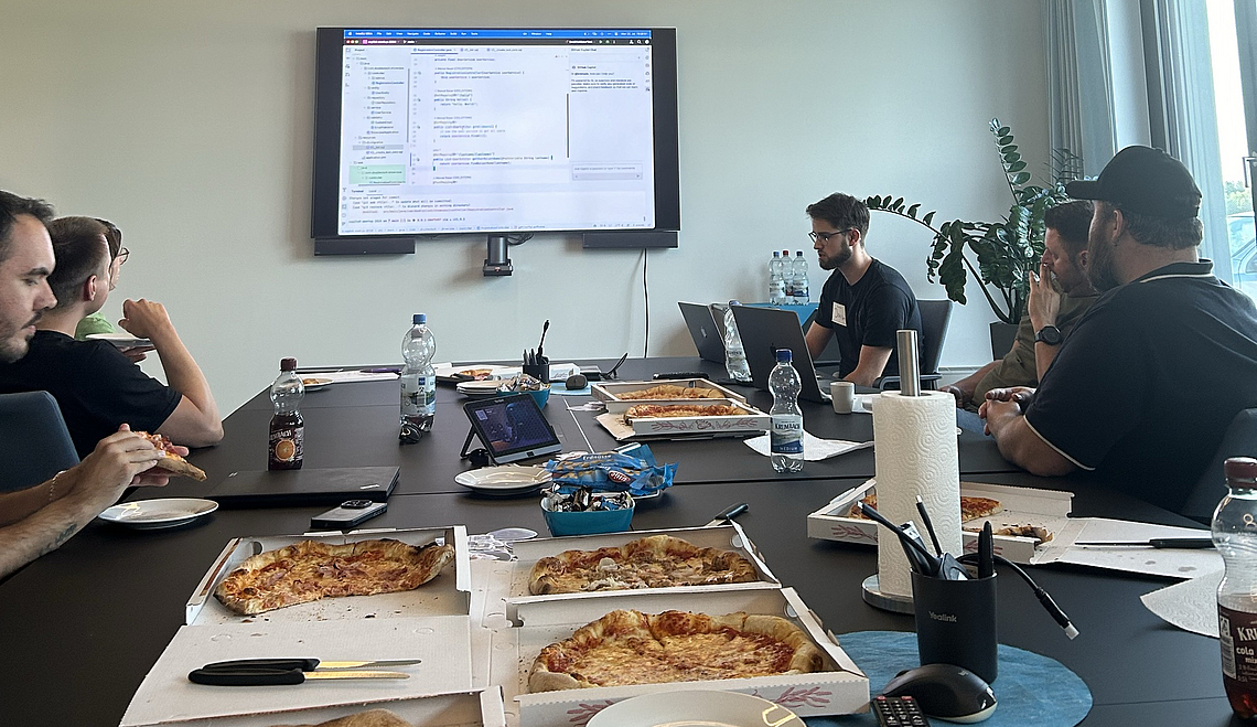 Gruppe isst Pizza im Besprechungsraum