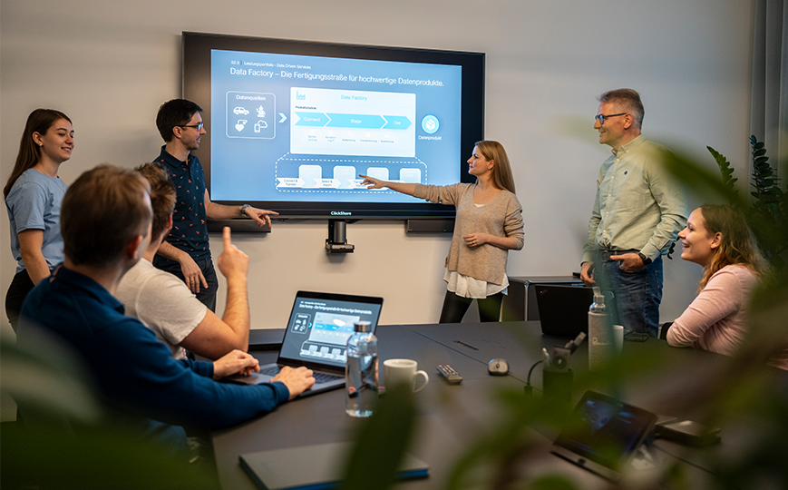 People who are in a meeting, a woman points at a screen with a graphic