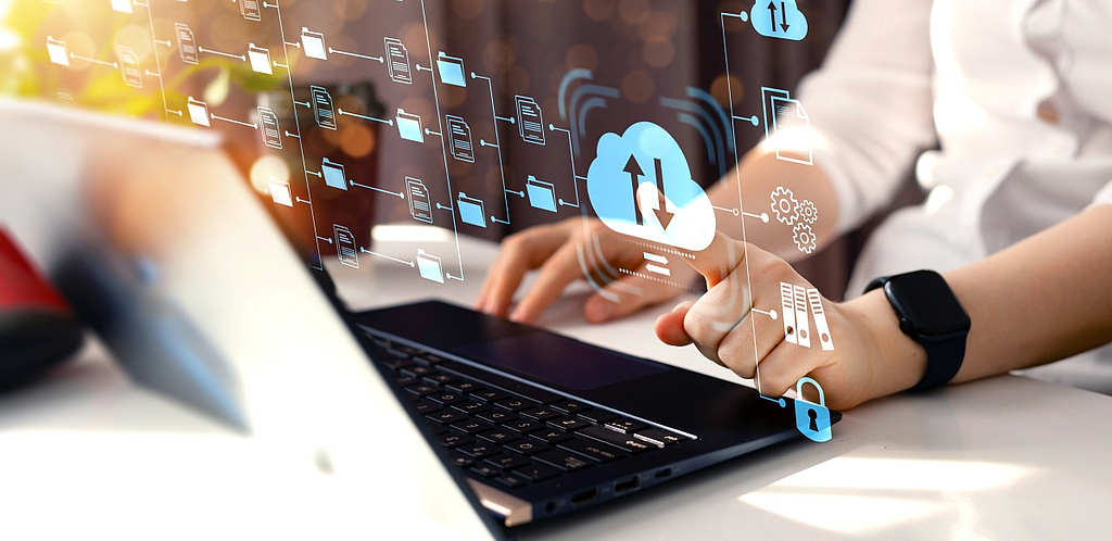 Person arbeitet am Laptop mit visualisierten Cloud- und Datenprozessen.