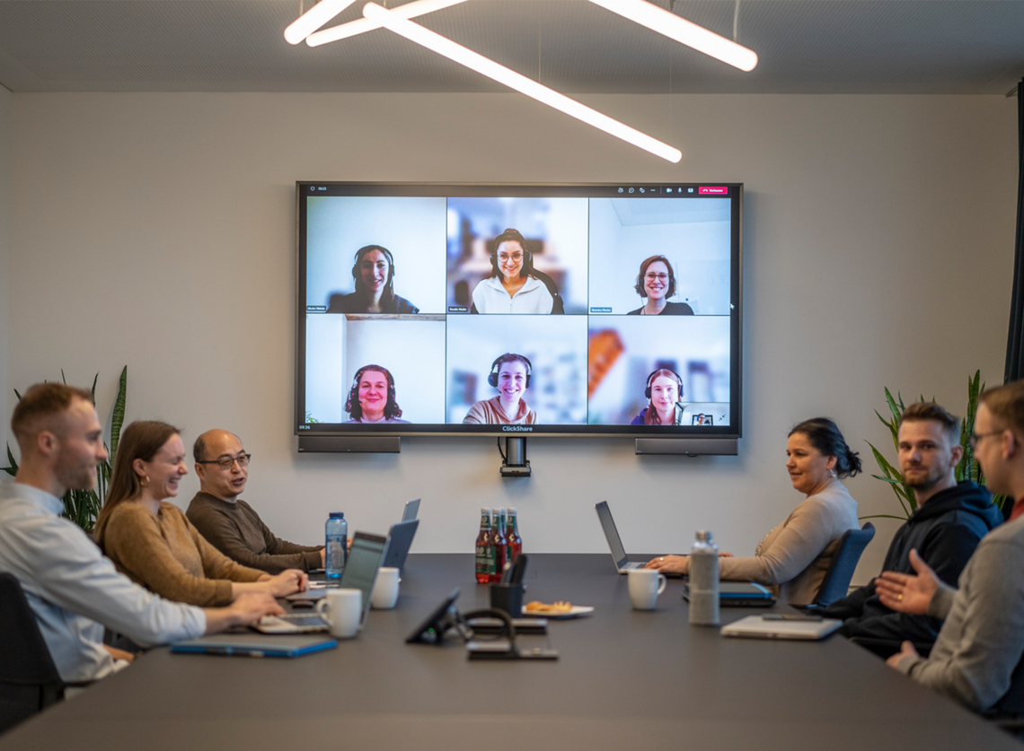 Personen am Tisch im Besprechungsraum mit remote Call
