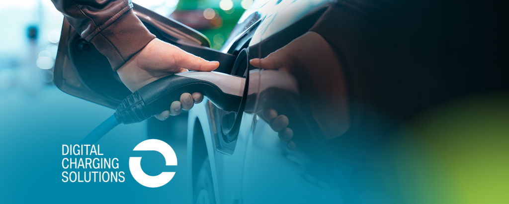 Eine Person steckt ein Ladekabel in ein Elektroauto; im Hintergrund sind unscharf weitere Fahrzeuge zu sehen. Unten links steht der Schriftzug „Digital Charging Solutions“ mit Logo vor einem blau-grünen Farbverlauf.
