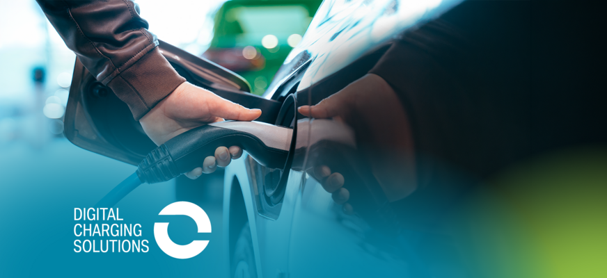 Eine Person steckt ein Ladekabel in ein Elektroauto; im Hintergrund sind unscharf weitere Fahrzeuge zu sehen. Unten links steht der Schriftzug „Digital Charging Solutions“ mit Logo vor einem blau-grünen Farbverlauf.