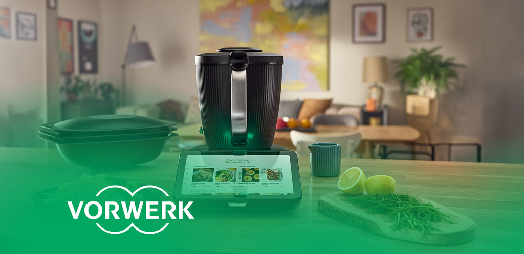 Thermomix mit Display zur Rezeptauswahl auf einer Küchenarbeitsfläche. „Vorwerk“-Logo unten links.