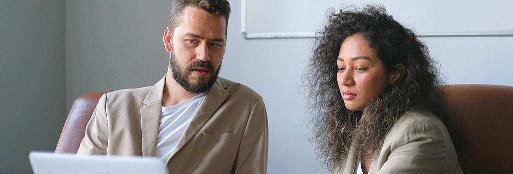 Compliance vs. Wachstum: Mann und Frau schauen auf einen Laptop