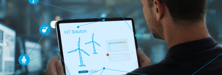 Keyvisual IoT: Man looking at a tablet with networked wind turbines