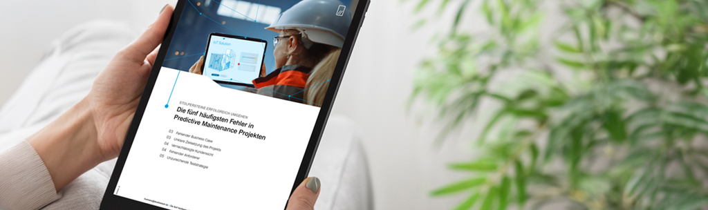 Person holding a tablet displaying a page about predictive maintenance and IoT content.