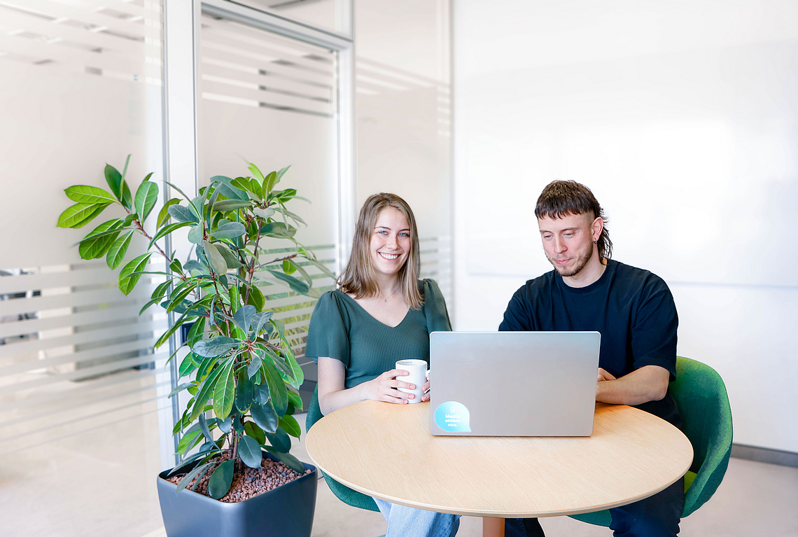 Two people sitting at a table with a laptop