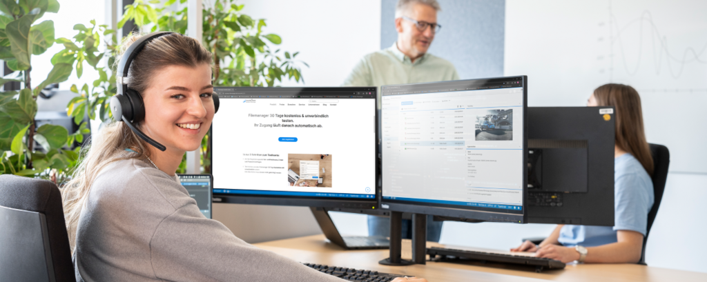 Junge Frau arbeitet mit dem Business Filemanager Testaccount und blickt über ihre Schulter den Betrachter an