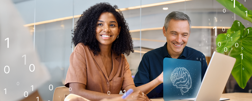 Zwei Personen sitzen gemeinsam an einem Laptop in einem modernen Büro. Vor ihnen steht ein Laptop. Über dem Laptop schwebt das Bildschirmbild mit einem Gehirn. Es schweben weitere 0 und 1 durch das Bild.